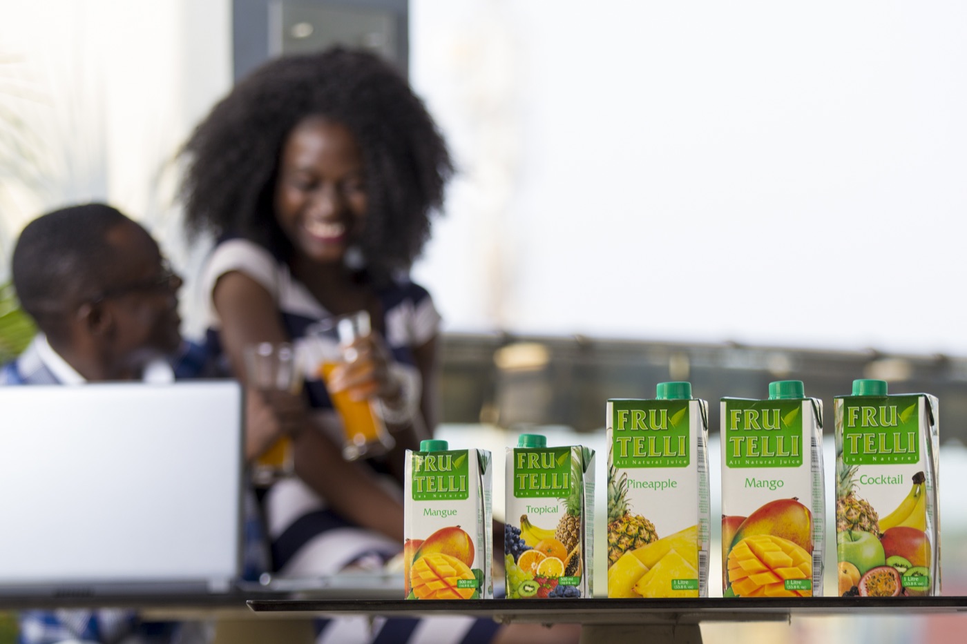 Frutelli juice cartons on a table with two people toasting